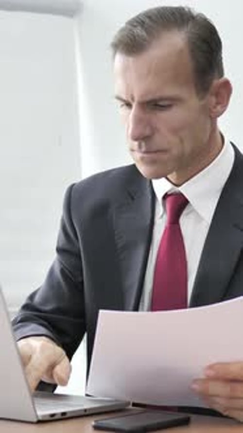 Businessman Working at Desk with Laptop and Documents