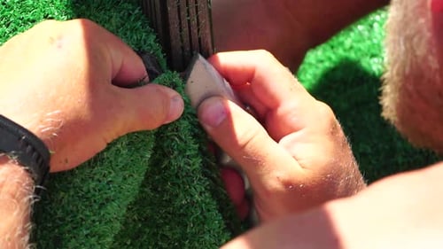 Man Cuting Artificial Grass Carpet with Knife Artificial Turf Close Up on Hands