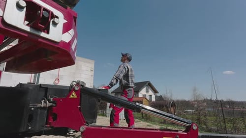 Bauarbeiter bedient Aufzug während eines Bauprojekts in einem Wohngebiet an einem sonnigen Tag