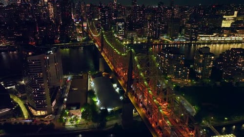 Tremendous Queensboro Bridge in orange and green lights. Lively traffic in neversleeping New York.