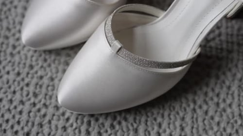 Talons de mariée en satin blanc avec bride à paillettes sur surface texturée
