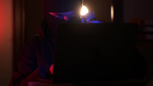 un hacker con pasamontañas roba dinero de una tarjeta de crédito