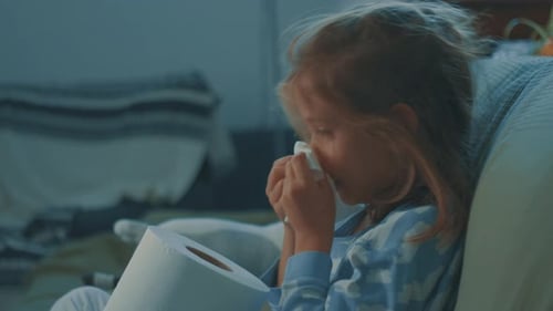Child Wipes Nose with Toilet Paper on Couch