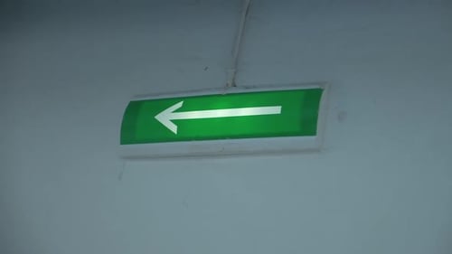 Glowing green arrow on wall. Arrow on green background lights up to indicate exit