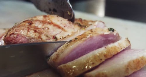 Amazing slow motion close-up shot of a chef slicing a freshly grilled barbecue loin of meat with a k