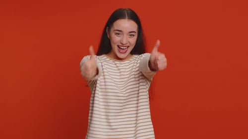 Enthusiastic Woman Gives Double Thumbs-Up on Red Background