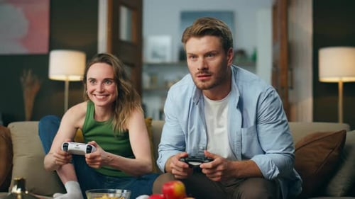 Smiling Couple Playing Video Games on Sofa