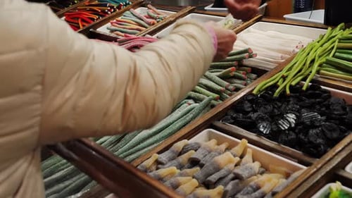 Imagens de doces de alcaçuz de cores diferentes no balcão de uma loja de doces durante uma feira de mulheres