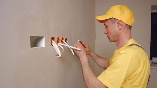 Man Working on Electrical Wiring in Wall