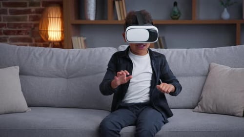Excited Boy Using Virtual Reality Headset on Sofa