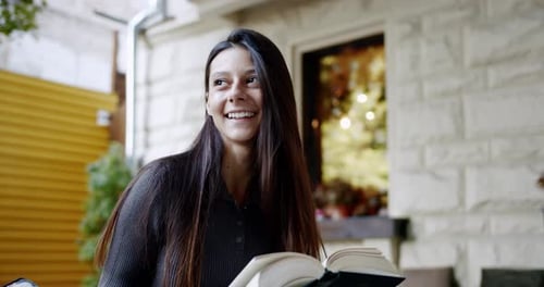 Young Brunette Reading Book on Street