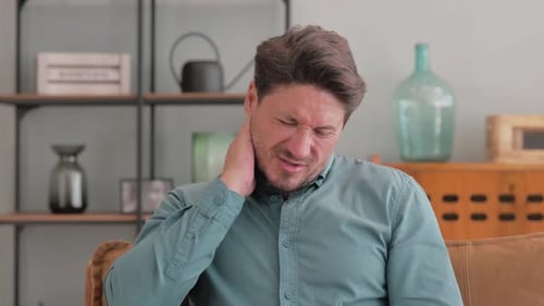 Adult Man Rubbing Stiff Neck in Home