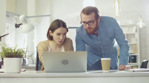 Portrait Shot of a Man and a Woman Discussing Work Looking Streight at the Camera. They are in the