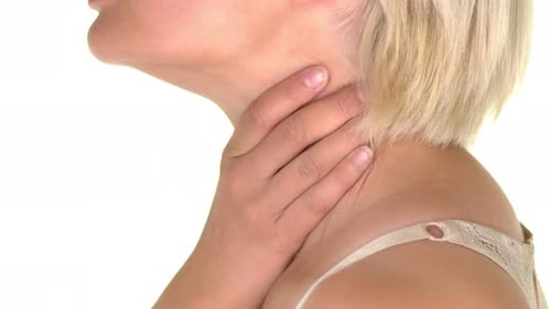 Close-up on the neck of a young woman suffering from sore throat and massaging with her hands.