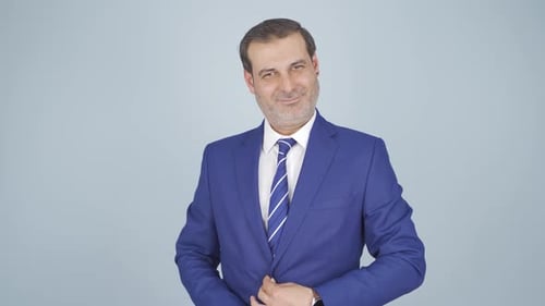 Confident Man Adjusts Blue Suit Jacket, Looks at Camera