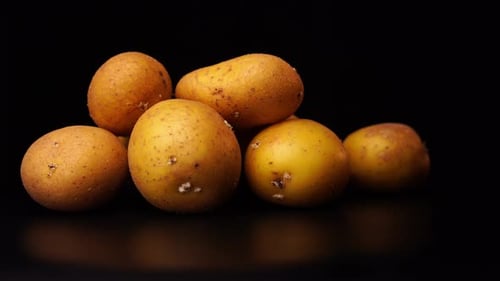 several potatoes rotate in front of a black background