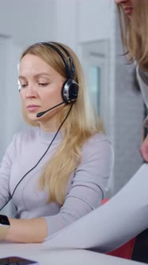 Konzentrierte Call-Center-Agentin mit Headset und Mikrofon bei der Bereitstellung von Büroschreibtischen