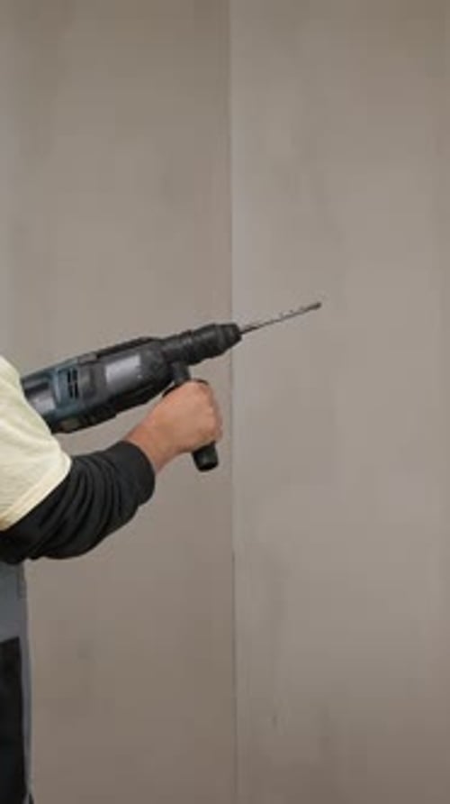 Man Using Hammer Drill on Wall