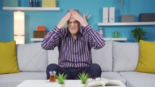 Senior Man Massaging Temples in Living Room