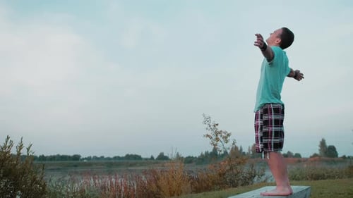 A Young Guy Enjoys Life At Dawn In Nature Behind A Lake Or A Quarry