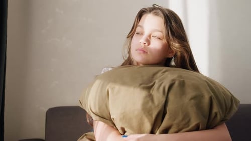 Teenage Girl Embraces Pillow in Sunny Room