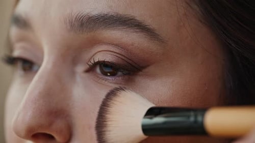 Brünette, die Gesichtspuder mit einem Make-up-Pinsel aufträgt, Nahaufnahme, elegantes, schickes Modell