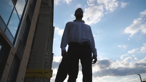 Man Walking Past Buildings with Blue Sky