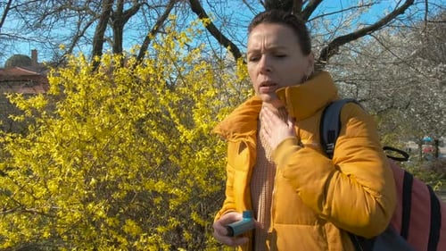 Femme malade près de buissons en fleurs jaunes