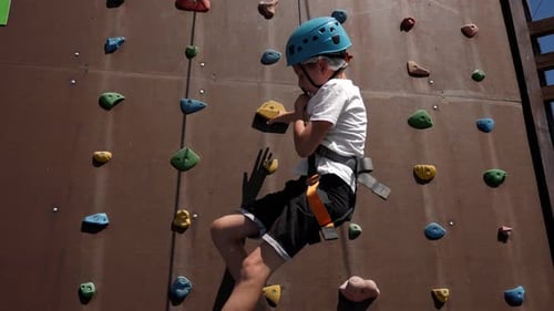 Young Boy Climbing a Rock Climbing Wall