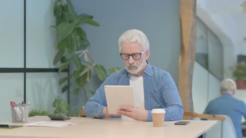 Senior Man Uses Tablet in Modern Office