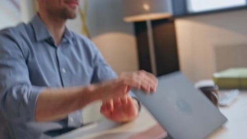 Man Closing Laptop and Clapping at Desk