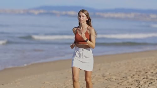 Young Woman is Running on the Beach on a Sunny Day