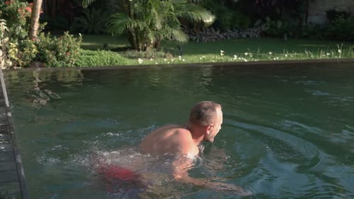 Man and woman swim together in the tropical hotel pool on a summer vacation