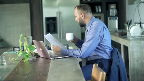 Junger Geschäftsmann liest Magazin und trinkt zu Hause Kaffee am Tisch der 30er