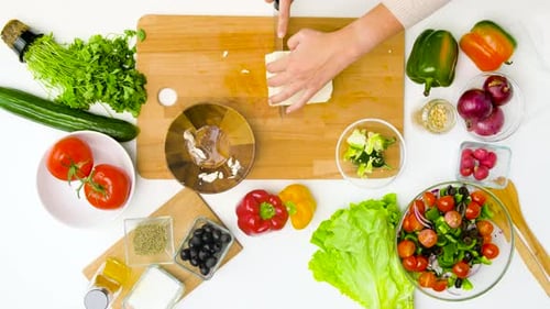 Frau bereitet zu Hause gesunden griechischen Salat zu
