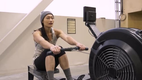 Woman Using Rowing Machine In Gym