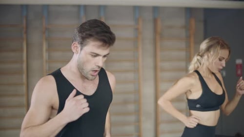 Fitness Couple Running on Treadmill Machine in Fitness Gym. Tired Trainers Finishing