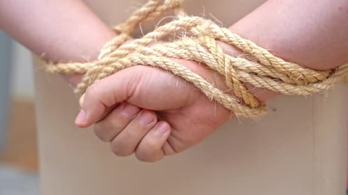 Hostage pulls hands tied behind back out of rope and frees