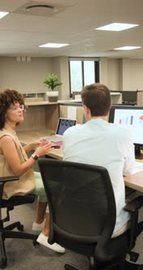 Vertical video: Pointing at bar chart diverse coworkers analyzing, discussing chart trends at desk