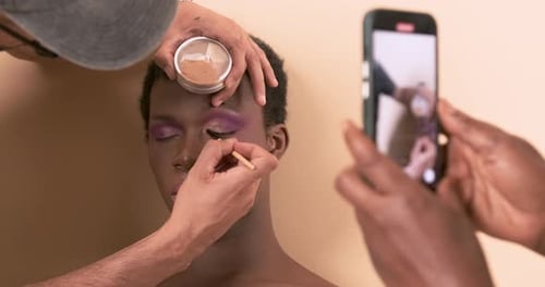 Makeup Artist Applying Eyeliner to Young Adult Model