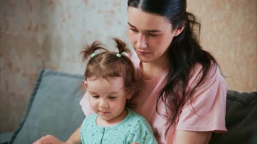 Woman and Child Reading a Book on Sofa