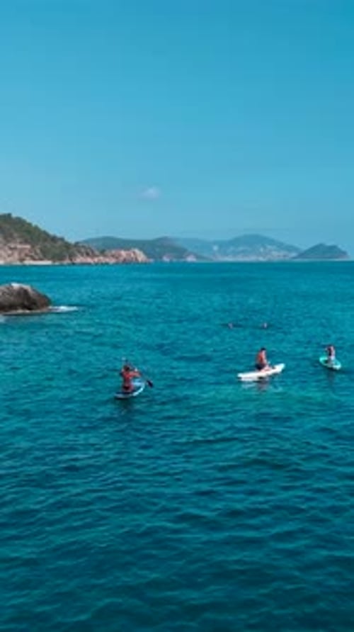 Vídeo vertical de remo no mar Mediterrâneo apresenta costas rochosas, águas claras e
