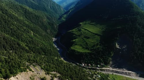 Aerial View of Serpentine River Through Forested Mountain Valley with Agricultural Fields Winding