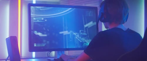 Teen gamer playing video game at night indoors