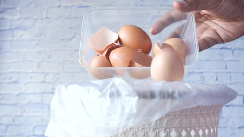 Hand throws eggshells into bin in the kitchen