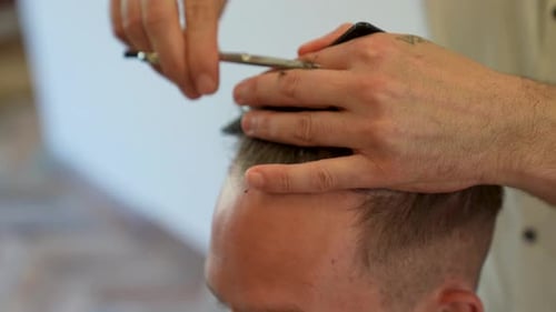 shallow depth of field close up of young caucasian mans hair being cut by professional barber