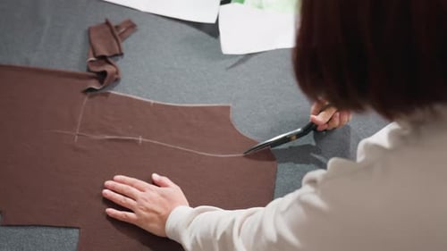 Woman Cutting Brown Fabric with Scissors