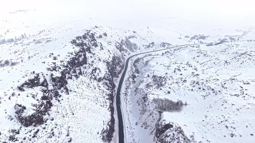 Aerial View of Vehicles Driving on a Snow Covered Mountain Road