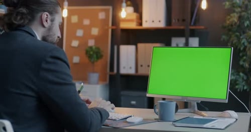 Geschäftsmann, der am Computer arbeitet und auf den Chroma Key Green Screen schaut, konzentriert sich auf die Unternehmensentwicklung
