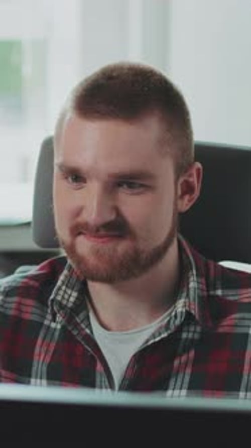A Young Bearded Man Sits at a Computer Works in the Office Feels Happy Colleague Company Concept